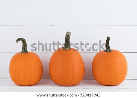 Three orange pumpkins on white wooden background, Halloween concept