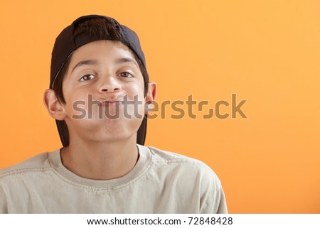 Bored Native American boy on orange background holding his breath