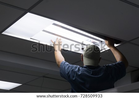 The man checking or changing Fluorescent light tube in the building. Royalty-Free Stock Photo #728509933
