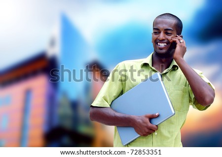 Young happy man or student with laptop and phone on the business background
