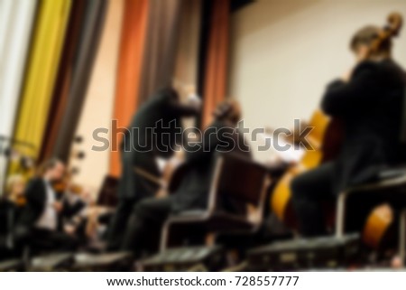 abstract blurred image. Artists symphony orchestra. Musician plays a musical instrument on the concert stage. Background for design, blur texture, actors on stage scene in concert.
