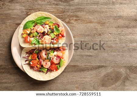 Plate with delicious shrimp tacos on wooden table