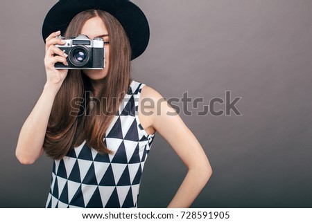 Stylish woman photographer with retro camera on the grey wall background. Image with copy space