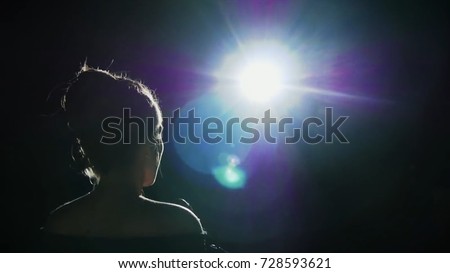 Girl in long gown performing on stage. the girl singing on the stage in front of the spotlight. Silhouette of singer standing on stage at microphone in night club Royalty-Free Stock Photo #728593621