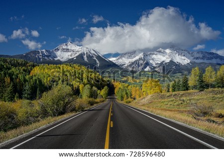 This is the picture of a road to mountain with clouds and blue sky with yellow leafs Aspen in Autumn, Colorado.