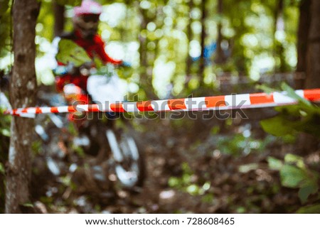 Close-up of barricade plastic rope with mountain bikes racing in jungle in blur background. Concept of focus during an accelerate in action sport