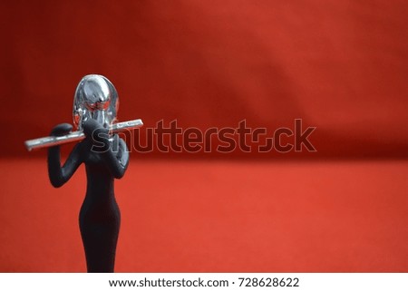 Toy girl with flute on the red background.