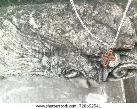Strength Christ cross necklace hanging on stone