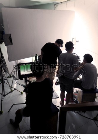 Behind the scene of silhouette film crew team shooting video commercial production and camera equipment in home studio.
