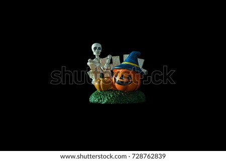 Halloween concept : Low key image of Plastic human skeleton model  and ceramic pumpkins isolated on black background 