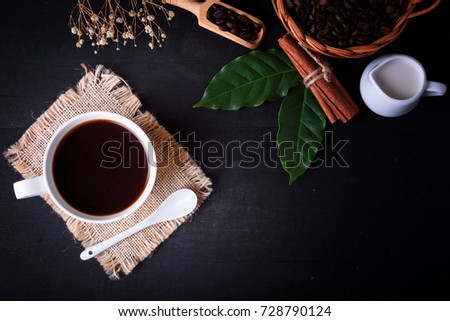 Top view Coffee Cup, Coffee Beans and Coffee leaf with Spoon on black wooden table and space for texture. 