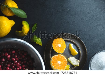 Cranberries in a bowl, tangerines and lemon in the left corner of the table