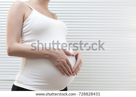 Picture of pregnant woman holding heart sign to one side