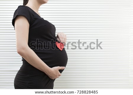 Picture of pregnant woman holding heart sign to one side