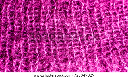violet warm wool knitted texture with aerial loops and clearly discernible pattern of knitting. colorful knitted fabric background close up. Warm wool scarf sweater clothes