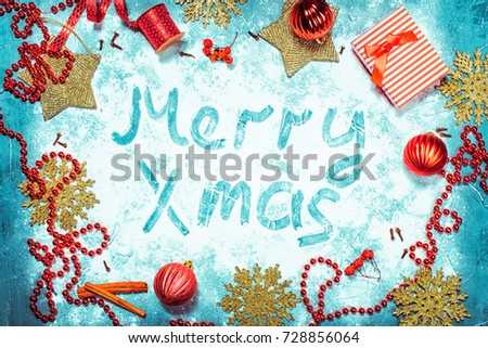 Christmas background with decorations and gift box. Board with snow flakes. Red baubles, garland.  Golden tree ornaments. Merry Xmas text