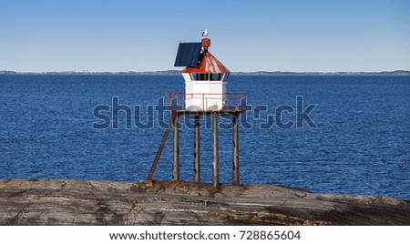 Traditional Norwegian lighthouse tower with solar battery and red top