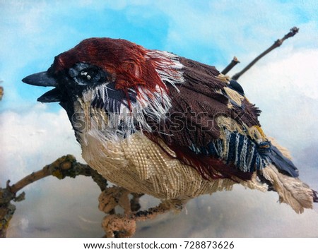 Fabric model sparrow bird perched on a branch