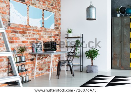 Fresh green potted plants placed in modern industrial loft with desk and handmade lampshade