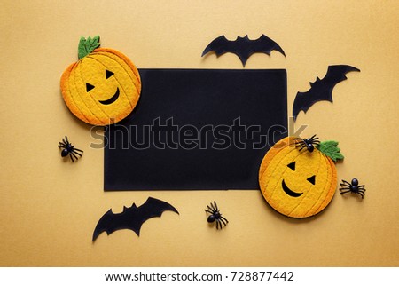 Black blank paper card with decorative pumpkins, spiders and bats on orange background. Space for text. Halloween background.