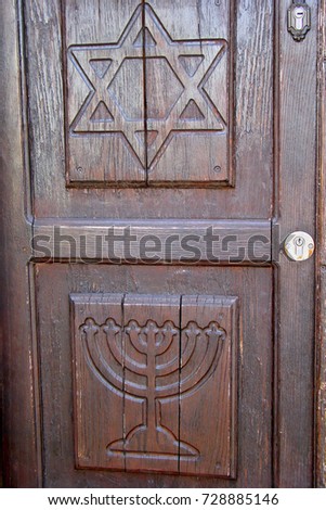 A door made of wood in the israeli city of safed shows the Jewish symbols the menorah and the star of david
