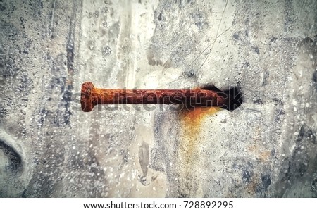 The rusted concrete nail stuck in the zinc sheet.