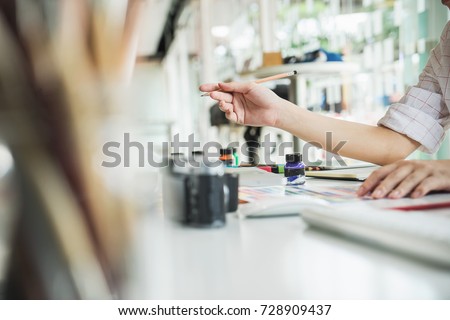 Young asian female designer using graphics tablet while working with computer at studio or office.	