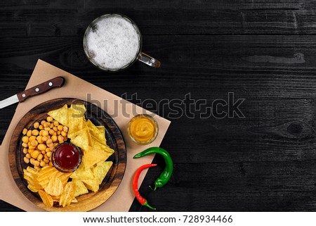 Lager beer and snacks on black wooden table. Nuts, chips. Top view with copyspace