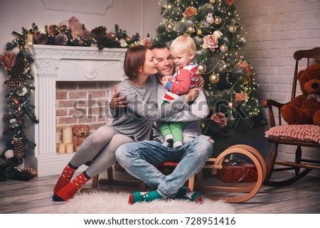 Happy smiling family at a home interior on background of the Christmas tree with gifts. Merry Christmas and Happy Holidays!