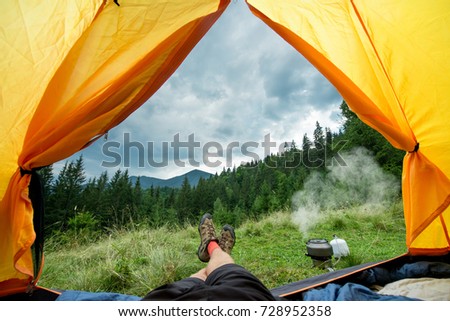 legs of the traveler in hiking boots in a tent outdoors Royalty-Free Stock Photo #728952358