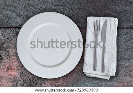 Empty plate and cutlery on mahogany wood.