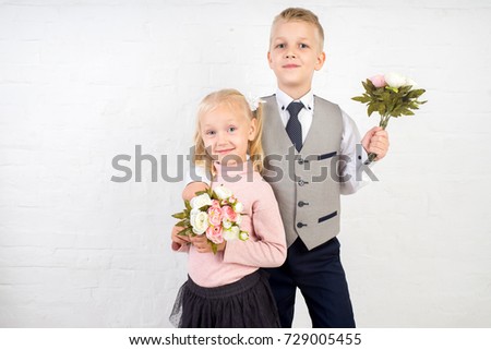 schoolboy schoolgirl with two small bouquets of flowers. school life concept. emotional children ready to see first teacher. Official dress code, new gray jacket, white shirt tie, black trousers skirt
