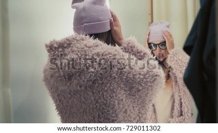 A young stylish hipster female tries on new jacket in the store, dancing and have fun