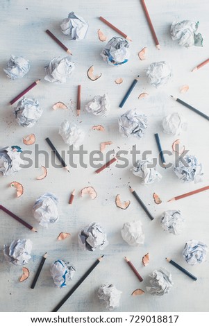 Writer workplace with minimalist flat lay pattern. Crumpled paper balls with pencils on a white wooden background, creative writing concept. High key still life.