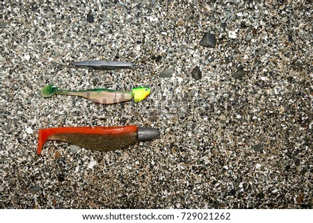 Different types of fishing baits lying against coarse-grained sand Royalty-Free Stock Photo #729021262