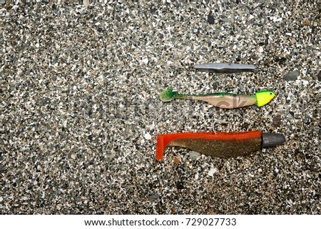Three fishing baits in different sizes lying in large-grained sand Royalty-Free Stock Photo #729027733