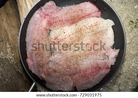 High angle close up view of fish fillets with spices on frying pan Royalty-Free Stock Photo #729031975