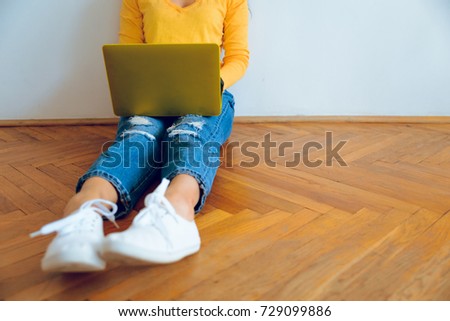 Young pretty smiling woman sitting on the floor with laptop