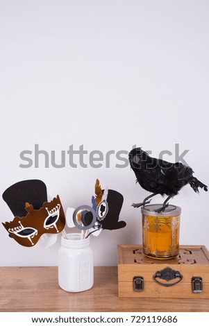 Halloween party prop, decorations. A decorative crow  and photo booth props  in a white ceramic jar. Copy space. 