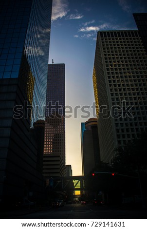 Before dawn sunrise down the center Houston Texas downtown financial district tall skyscrapers , hotels , condos , and office building rise high into the sky with skywalk bridge over the street