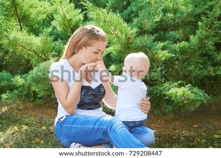Happy beautiful mother and baby daughter or son enjoying in the summer park