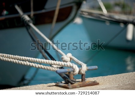 Yacht moored in marina.
A picture of a rope tying the yacht to the pier.