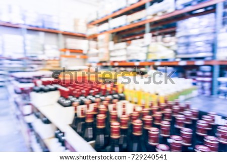 Blurred image close-up row of wine bottles in cellar, champagne section of modern distribution warehouse. Defocused storehouse interior aisle. Beverage alcohol concept background. Vintage tone