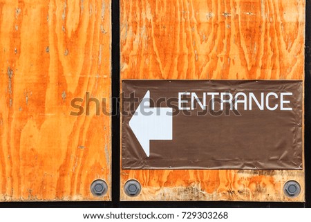 The signboard of entrance on the wall with plywood.