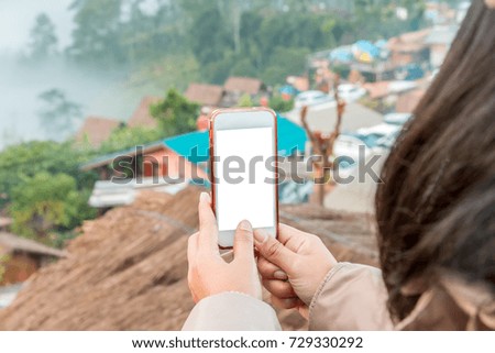 Hand holding cell phone to take a photo view of city on the mountain , blank screen on white