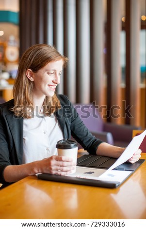 Smiling Woman Working and Drinking Coffee in Cafe