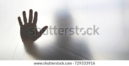 Silhouette of a ghost hand behind transparent plastic
