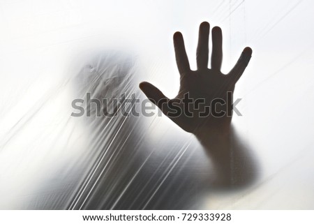 Silhouette of a ghost hand behind transparent plastic