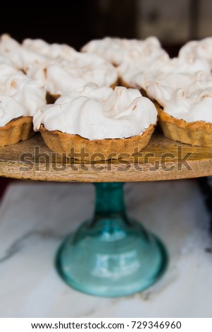 Miniature petit four lemon meringue pies on a cork desert tray.