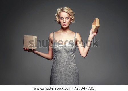 Woman with gift box open in hands over gray background